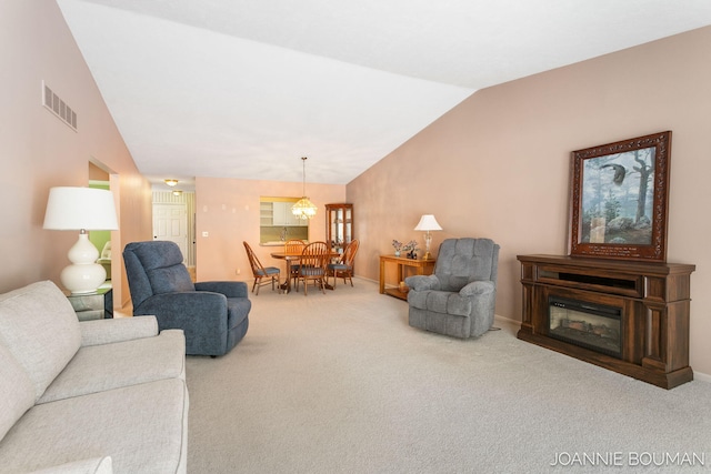 living room featuring carpet floors, a glass covered fireplace, visible vents, and vaulted ceiling