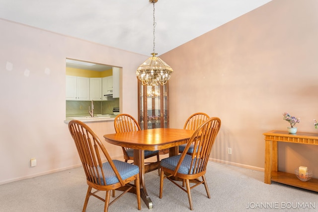 dining room featuring baseboards, a chandelier, and light colored carpet