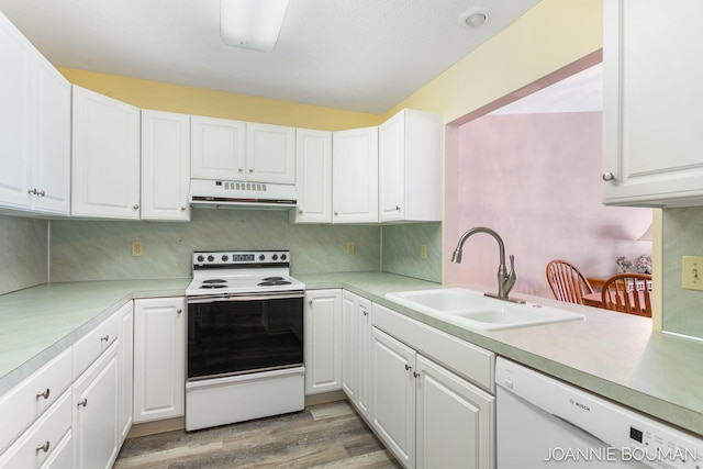 kitchen featuring white appliances, white cabinets, a sink, and under cabinet range hood