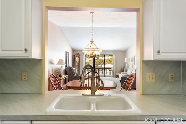 kitchen featuring a chandelier, light countertops, a sink, and white cabinetry