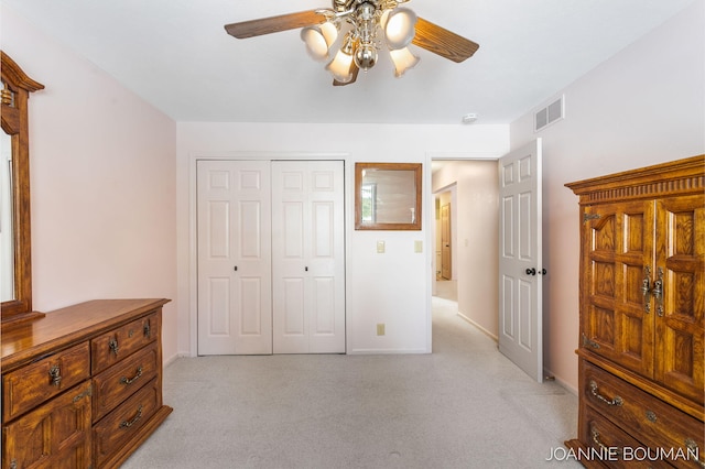 bedroom with a closet, light colored carpet, visible vents, a ceiling fan, and baseboards