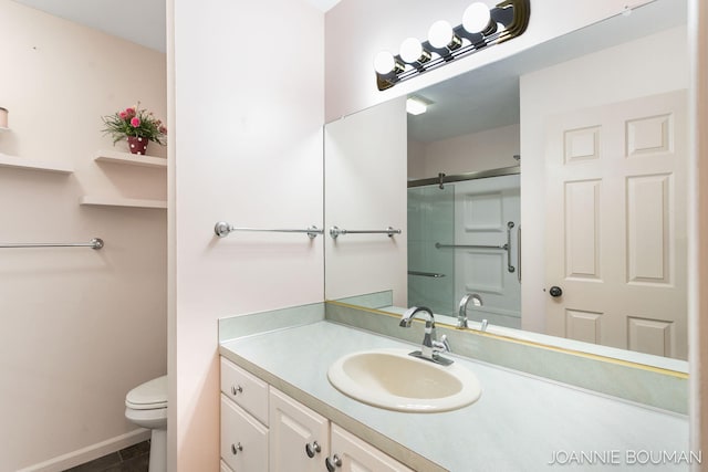 bathroom featuring vanity, a shower stall, toilet, and baseboards