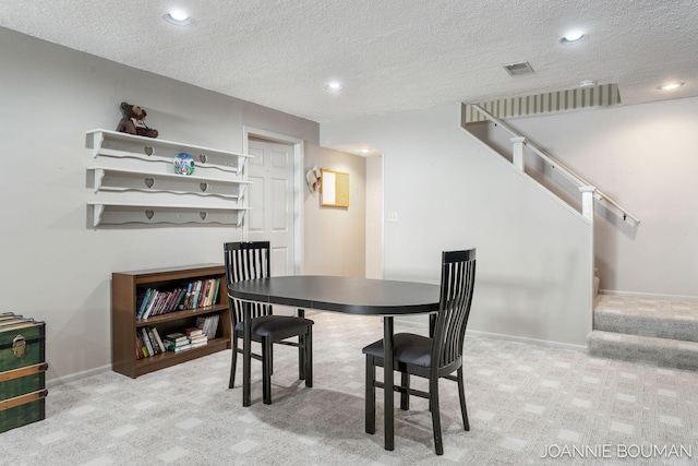 dining area featuring a textured ceiling, carpet flooring, visible vents, baseboards, and stairway