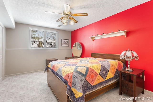 carpeted bedroom featuring a ceiling fan, visible vents, a textured ceiling, and baseboards