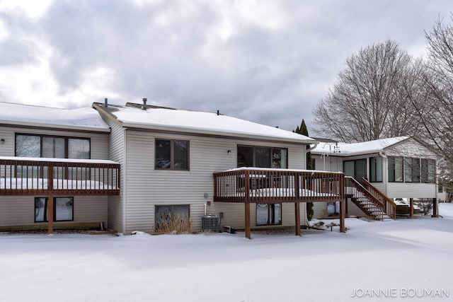 snow covered house featuring a deck, stairway, and cooling unit