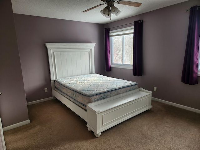 bedroom featuring a textured ceiling, dark colored carpet, a ceiling fan, and baseboards