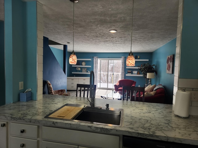 kitchen featuring light stone counters, a sink, white cabinets, dishwasher, and decorative light fixtures