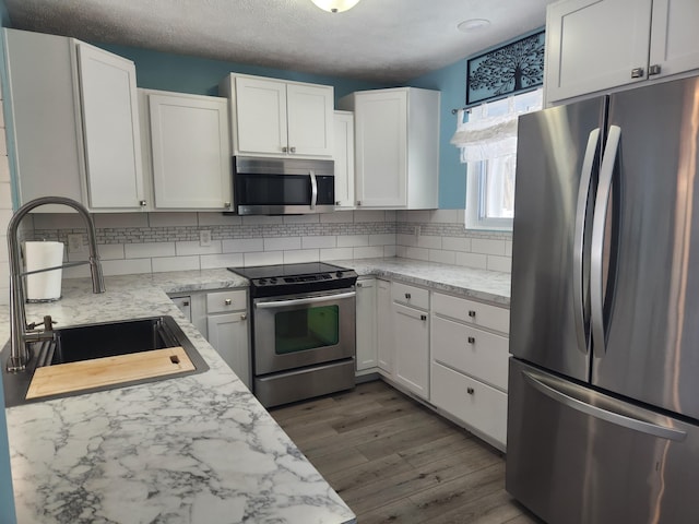 kitchen featuring dark wood-style flooring, a sink, white cabinetry, appliances with stainless steel finishes, and backsplash