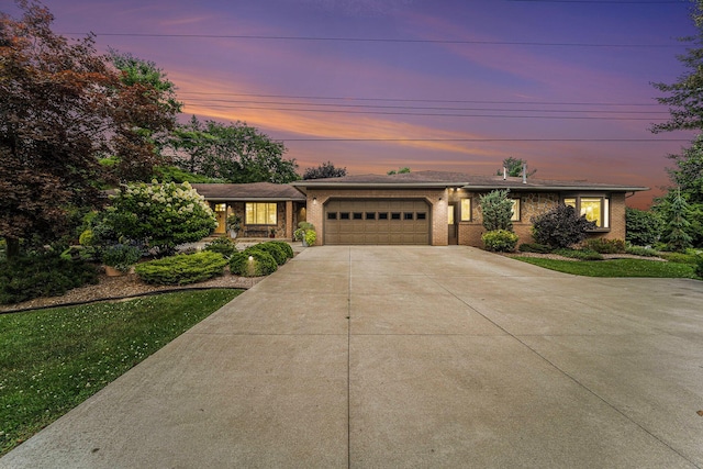 view of front of home with a garage, concrete driveway, brick siding, and a front lawn