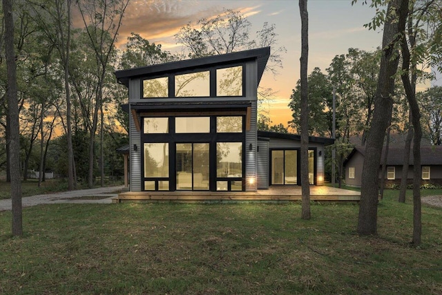 back of house at dusk featuring a yard