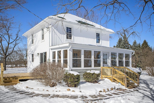 snow covered property featuring board and batten siding and a sunroom