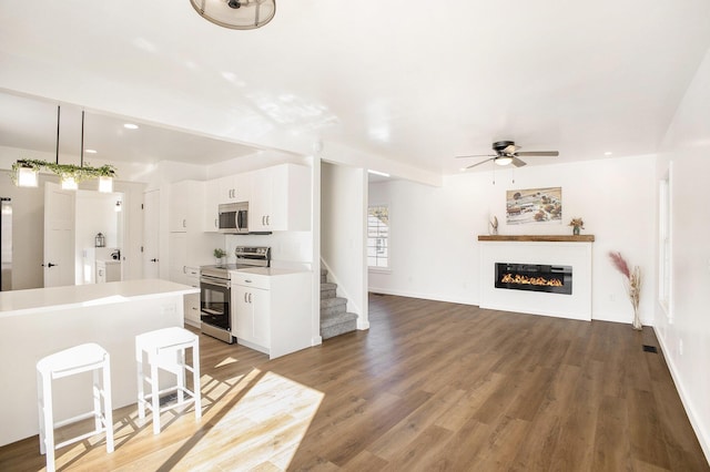 kitchen with stainless steel appliances, light countertops, white cabinetry, a kitchen island, and washer / dryer