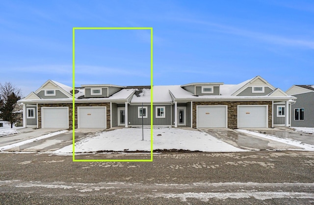 view of property with stone siding, driveway, and an attached garage