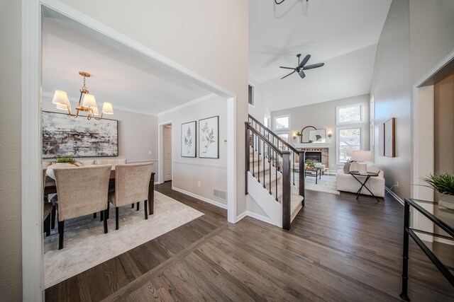 entrance foyer with a fireplace, crown molding, visible vents, dark wood-type flooring, and stairs