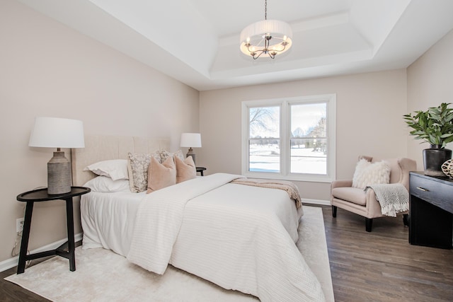 bedroom featuring a chandelier, a tray ceiling, dark wood finished floors, and baseboards