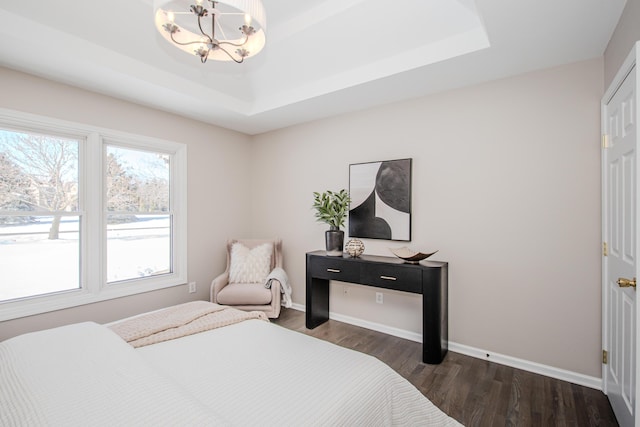 bedroom with a raised ceiling, baseboards, and dark wood-style flooring