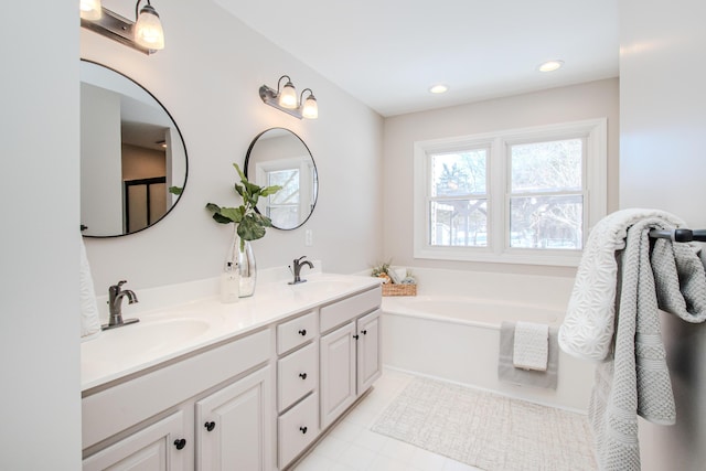 bathroom featuring recessed lighting, a garden tub, a sink, and double vanity