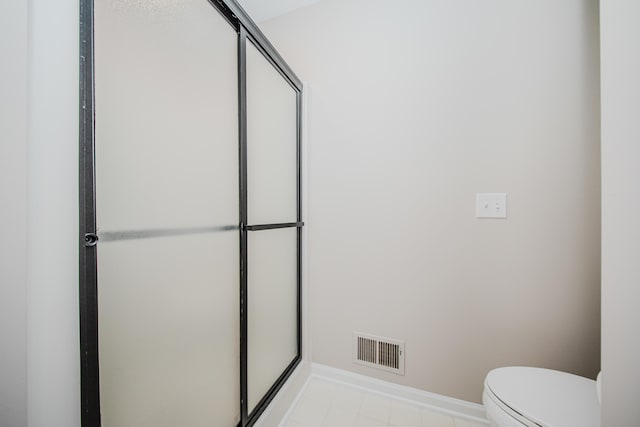 bathroom featuring toilet, baseboards, visible vents, and a shower with shower door