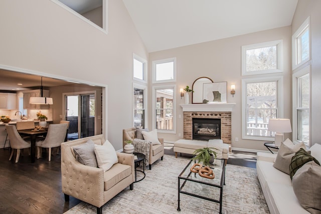 living room featuring baseboards, a fireplace, high vaulted ceiling, and wood finished floors