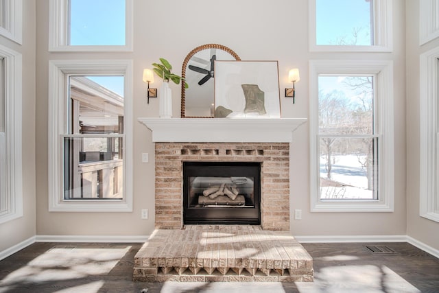 interior details with baseboards, a fireplace, visible vents, and wood finished floors