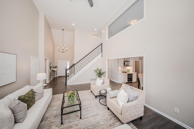 living area with a towering ceiling, baseboards, stairway, and wood finished floors