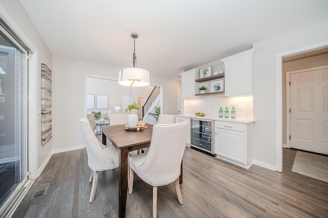 dining area featuring wine cooler, a dry bar, wood finished floors, and visible vents