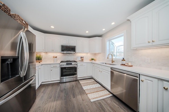 kitchen with dark wood-style floors, light countertops, appliances with stainless steel finishes, white cabinetry, and a sink