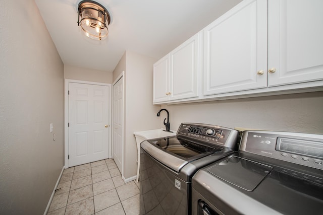 clothes washing area with light tile patterned flooring, a sink, baseboards, independent washer and dryer, and cabinet space