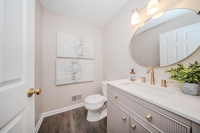 bathroom featuring toilet, wood finished floors, visible vents, vanity, and baseboards