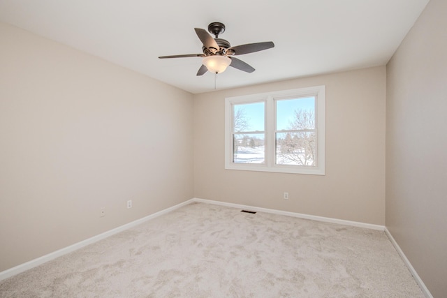 spare room featuring baseboards, ceiling fan, visible vents, and light colored carpet