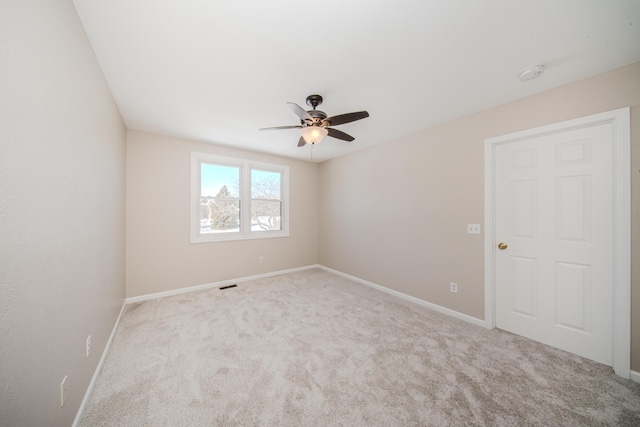 spare room featuring baseboards, visible vents, ceiling fan, and light colored carpet