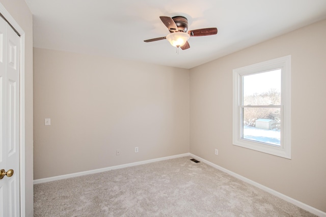 unfurnished room with a ceiling fan, light carpet, visible vents, and baseboards