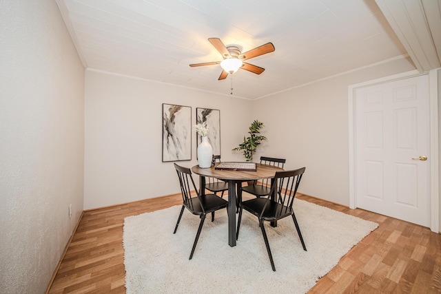 dining room with crown molding, light wood-style flooring, and a ceiling fan