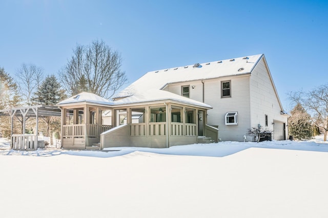 snow covered back of property with a garage and a porch