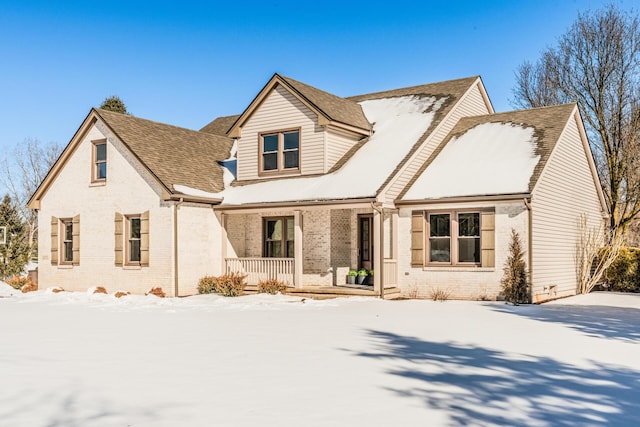 view of front of home featuring covered porch, a shingled roof, and brick siding