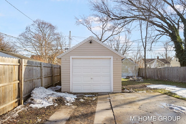 detached garage featuring concrete driveway and fence