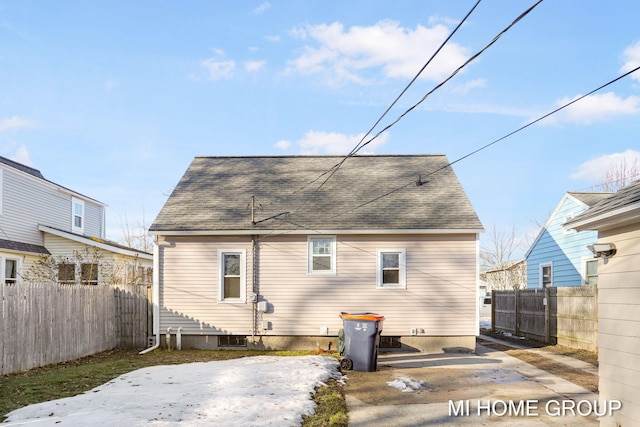 rear view of property with a shingled roof and fence