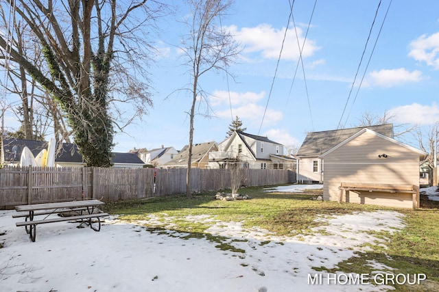 yard layered in snow featuring a residential view, fence, and an outbuilding