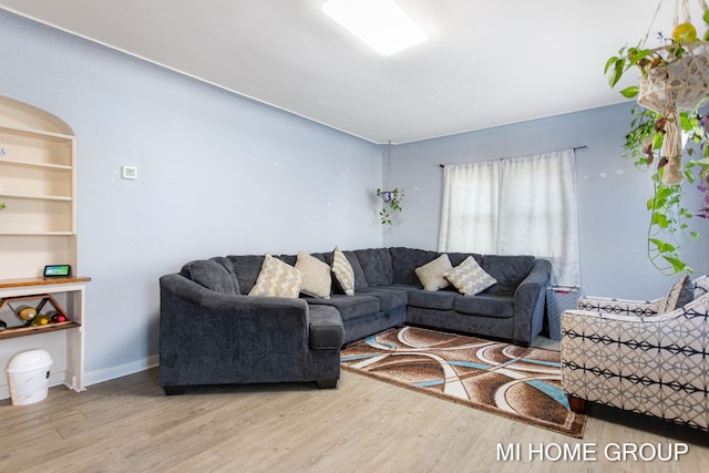 living area featuring built in features, baseboards, and wood finished floors