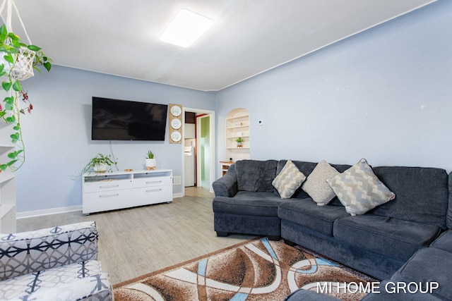 living room with arched walkways, light wood finished floors, baseboards, and built in features