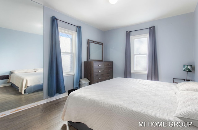 bedroom featuring multiple windows, wood finished floors, and baseboards