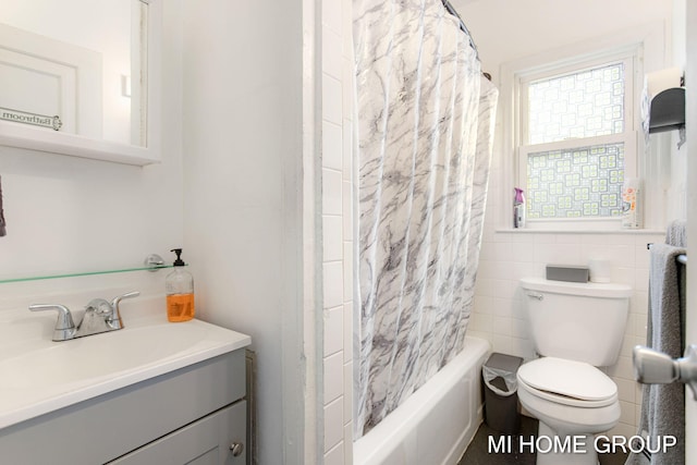 full bathroom with tile walls, vanity, toilet, and shower / tub combo with curtain