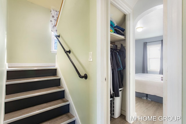 stairway with arched walkways and wood finished floors