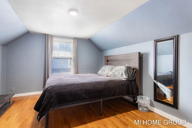 bedroom with lofted ceiling, baseboards, and wood finished floors