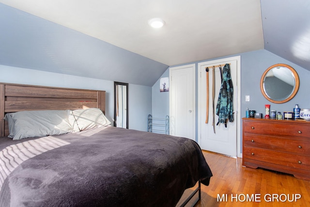 bedroom featuring light wood-style flooring and vaulted ceiling