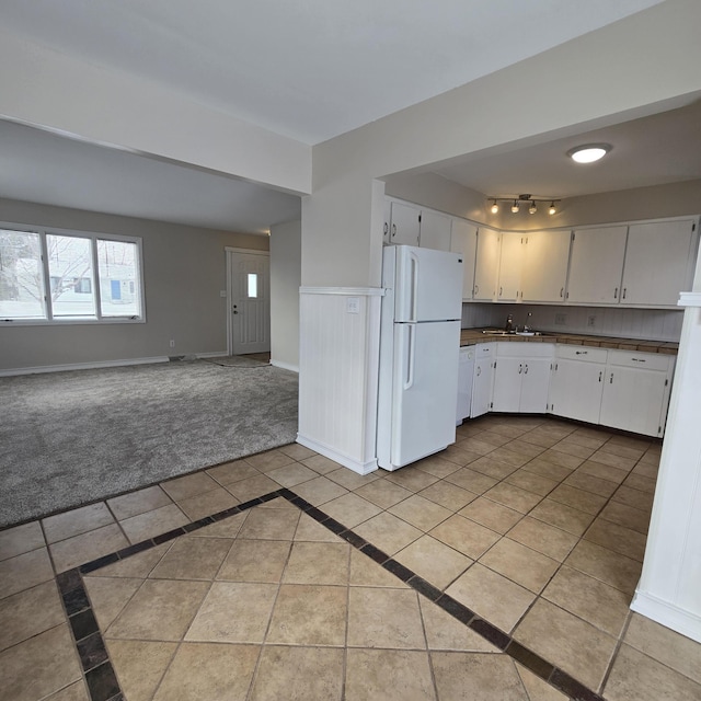 kitchen featuring light tile patterned floors, white appliances, baseboards, open floor plan, and white cabinets