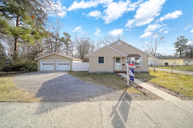 bungalow featuring an outbuilding, fence, a front yard, and a detached garage