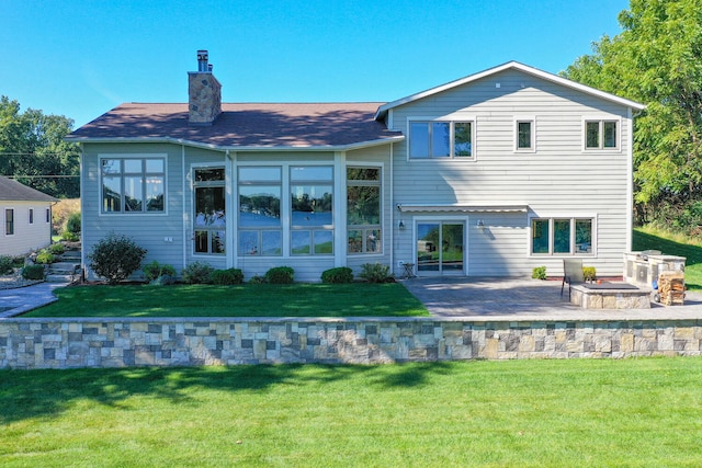 back of house featuring a chimney, a lawn, and a patio