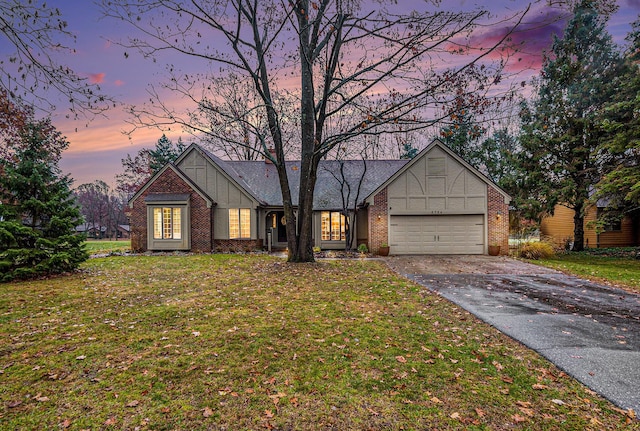 view of front of property with a front yard, brick siding, driveway, and an attached garage