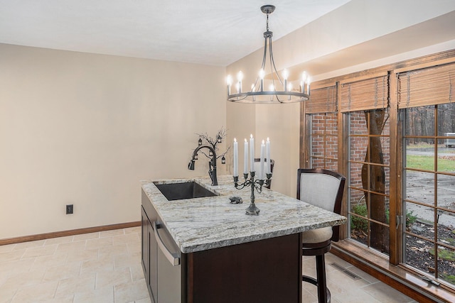 kitchen featuring decorative light fixtures, a notable chandelier, a sink, dishwasher, and baseboards